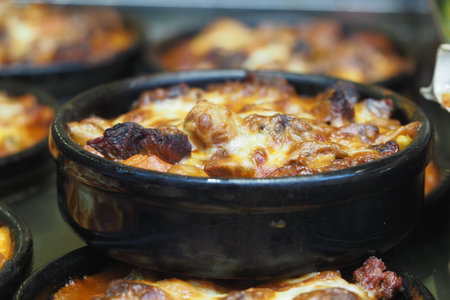 Delicious baked dish with melted cheese served in a black bowlの写真素材