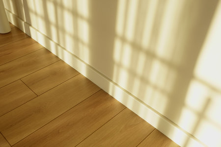 Shadows cast on wooden floor from window at morning light timeの写真素材