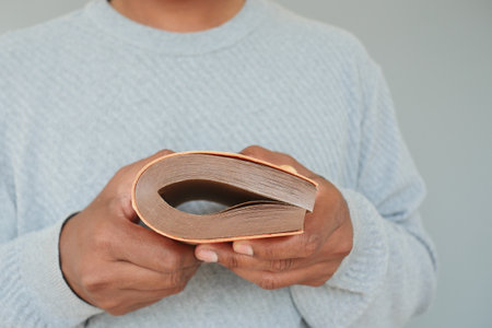 Person holding a worn book with visible pages in natural lightの写真素材