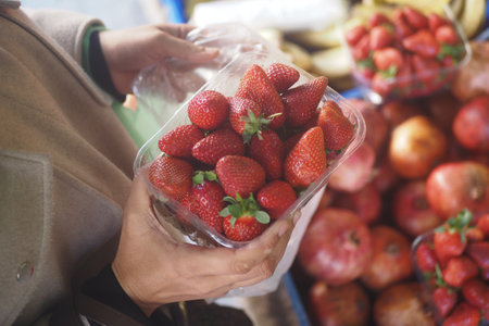 Fresh strawberries in hand at the local market during the morningの写真素材