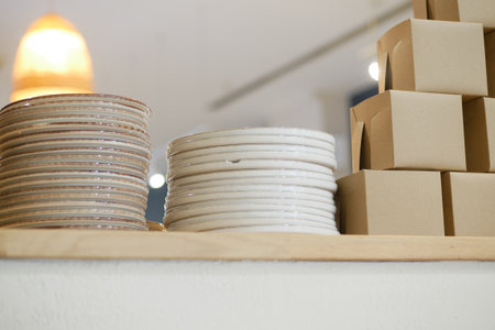Stacked plates and takeout boxes in a modern cafe settingの写真素材