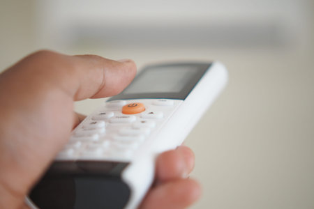 Remote control in hand adjusting air conditioning settings indoors