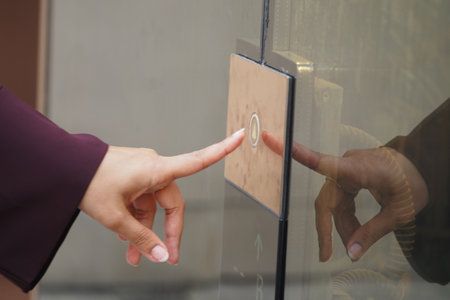Person pressing elevator button in a modern building lobbyの写真素材