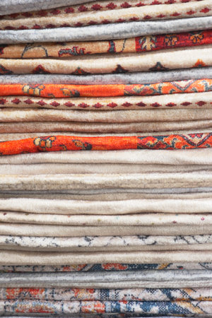 Colorful rug stacked in intricate patterns at a local marketの写真素材