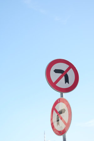 No U turn signs against a clear blue sky in a traffic areaの写真素材