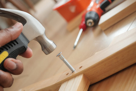 DIY home project involving hammering a screw into woodの写真素材