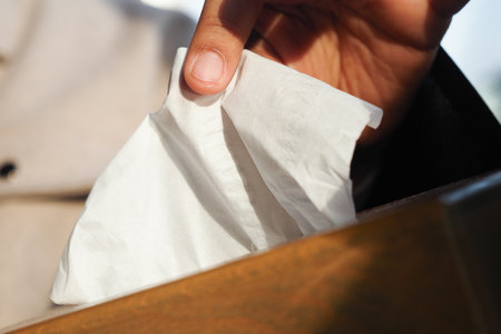 Hand reaching for a tissue in a wooden box outdoors in bright daylightの写真素材