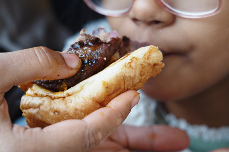 Child enjoying a delicious sandwich during a family gatheringの写真素材