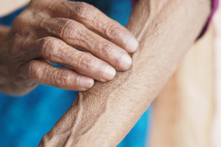 Close-up of an elderly hand resting on the arm in natural light
