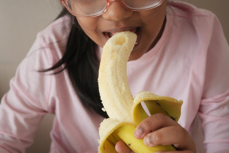 Young girl enjoys a banana snack during the afternoonの写真素材