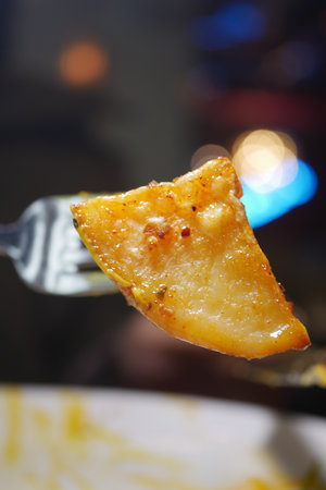 Delicious golden potato slice on a fork ready to enjoyの写真素材