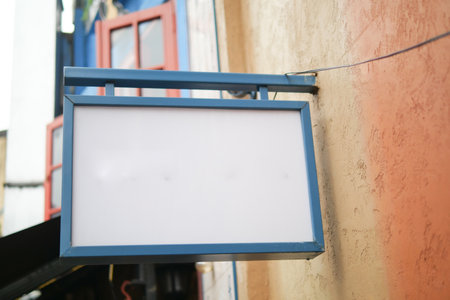 Blank sign hanging outside colorful building in busy streetの写真素材