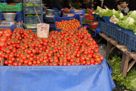 Fresh red tomatoes stacked at a bustling market in autumnの写真素材