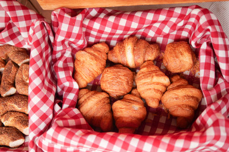 Freshly baked croissants in a woven basket at a market stallの写真素材