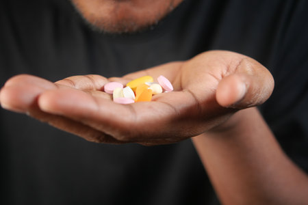 Person holding colorful pills in palm under soft lightingの写真素材