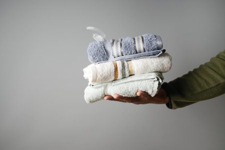 Freshly folded towels stacked in hand showcasing neat organizationの写真素材