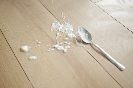 Spilled yogurt on wooden floor with spoonの写真素材