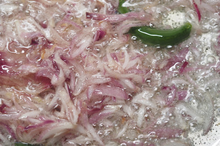 Slicing onions and green peppers cooking in bubbling hot oilの写真素材