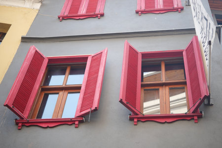 Bright red shutters adorn a historic building in a lively urban areaの写真素材
