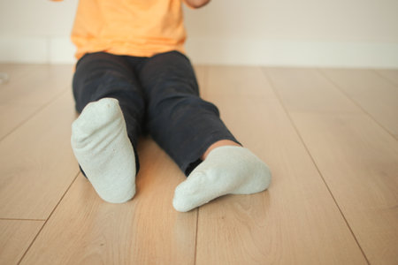 Child sitting on wooden floor, playing with toys in bright roomの写真素材