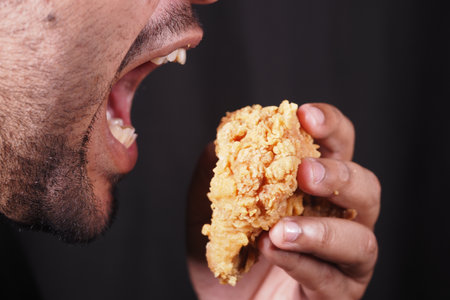Enjoying a crispy fried chicken piece in a casual settingの写真素材
