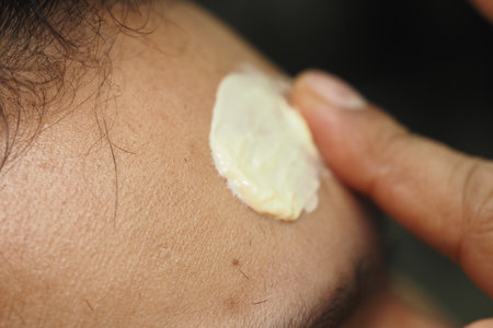 A hand is moisturizing the forehead with a creamy substance for hydrationの写真素材