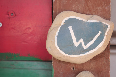 Rock with letter W painted in blue and white on wooden surfaceの写真素材