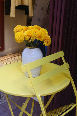 Bright yellow flowers in a vase on a small table in a cozy cafeの写真素材