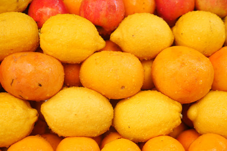 Bright yellow lemons and oranges stacked at a market displayの写真素材
