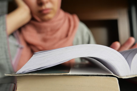 Woman studying intently with an open book in a cozy spaceの写真素材