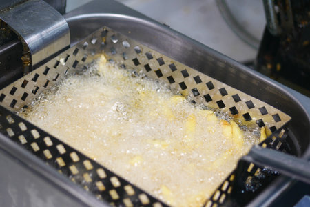 Fried potatoes cooking in hot oil in a small kitchenの写真素材