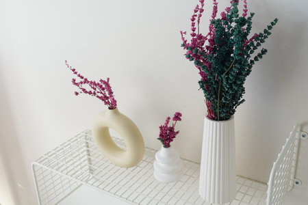 Vibrant dried flowers displayed in modern vases on a shelfの写真素材