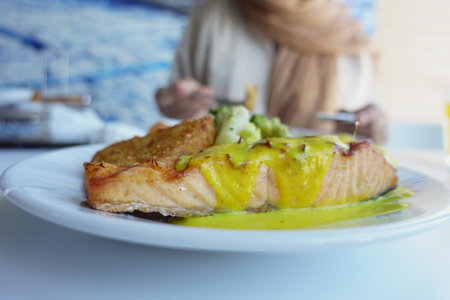 Freshly cooked salmon with vibrant sauce served in a restaurantの写真素材