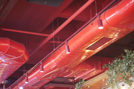 Modern interior design features vibrant red ductwork and lightingの写真素材