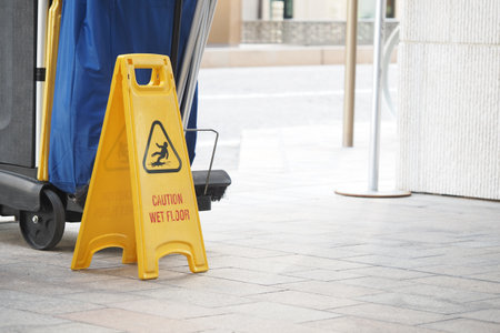 Caution sign indicating wet floor near cleaning equipment outsideの写真素材