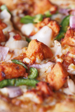 Fresh pizza topped with succulent ingredients in a bustling kitchenの写真素材