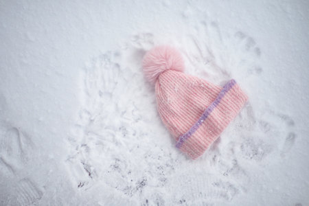 Winter hat resting on freshly fallen snow with handprints aroundの写真素材