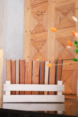 Books arranged neatly in a wooden holder on a table with decorationの写真素材