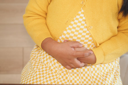 Child suffering stomach pain sitting on sofaの写真素材