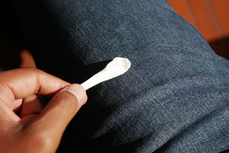 Close-up of hand holding chewing gum on denim jeansの写真素材