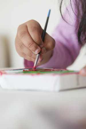 Child painting on a canvas with brush in a bright roomの写真素材