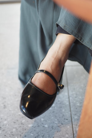 Black patent leather shoe worn by person seated indoorsの写真素材
