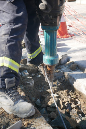 Construction worker using jackhammer on pavement in a city areaの写真素材