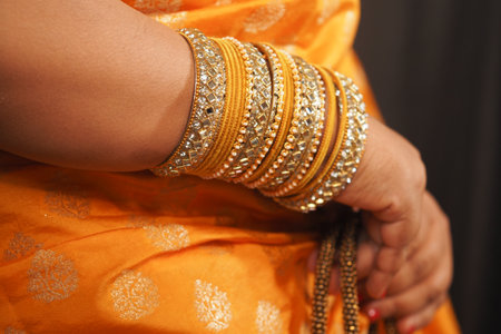 Elegant gold bangles complement vibrant orange attire at celebrationの写真素材