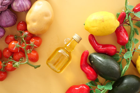 Fresh vegetables and oil arranged on a vibrant yellow backgroundの写真素材