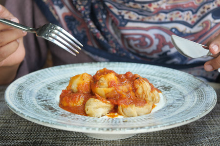 Enjoying a savory meal of dumplings in rich tomato sauceの写真素材