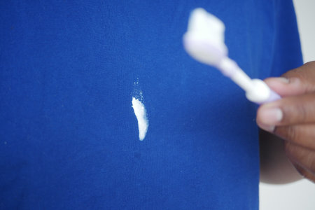 Toothpaste stain removal technique on a blue shirt fabricの写真素材