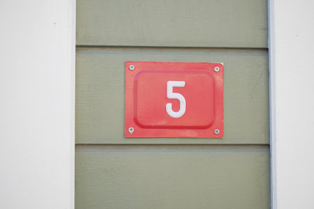 House number five on a green wall in bright daylightの写真素材