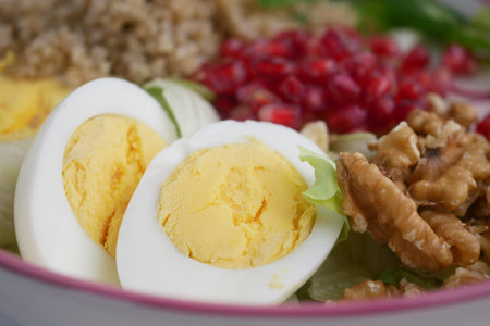 Delicious salad bowl featuring eggs, pomegranate, and walnutsの写真素材