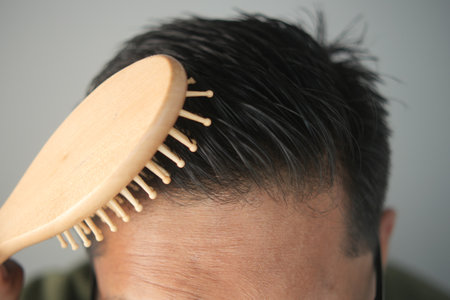 Man grooming with wooden hairbrush in indoor settingの写真素材